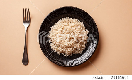 Cooked White Rice in Black Bowl on Peach Background 129165696