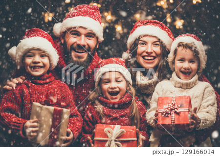 Joyous Family Celebration with Santa Hats and Giftboxes in a Winter Wonderland 129166014