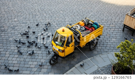 Aerial View of a Yellow Three Wheeled Vehicle Loaded With Luggage on Cobblestone Street 129166765