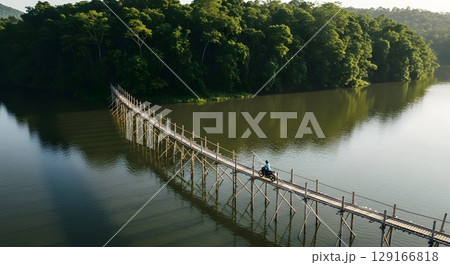 Aerial View Of Long Wooden Bridge Over Tranquil Lake With Green Trees Sunlight 129166818