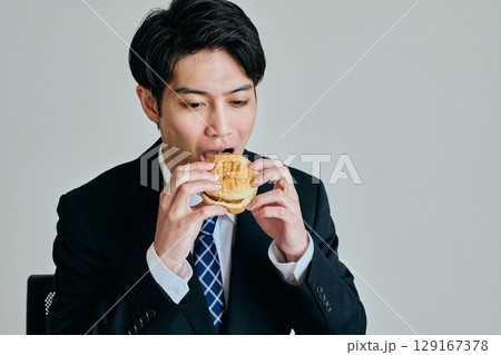 ハンバーガーを食べる若い男性 129167378