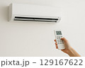 エアコンのリモコンを持ち操作する手 129167622