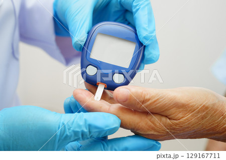 Asian doctor using digital glucose meter for check sample blood sugar level to treatment diabetes. Asian doctor using digital glucose meter for check sample blood sugar level to treatment diabetes. 129167711