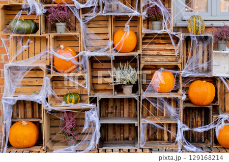 Group of orange pumpkins in wooden boxes in autumn outside. Thanksgiving or Halloween holiday autumn decoration. House entrance in festive seasonal decor. Fall 129168214