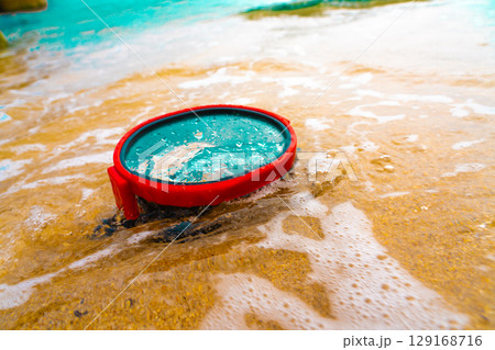 A diving mask lies on a sandy beach and is washed by waves of water 129168716