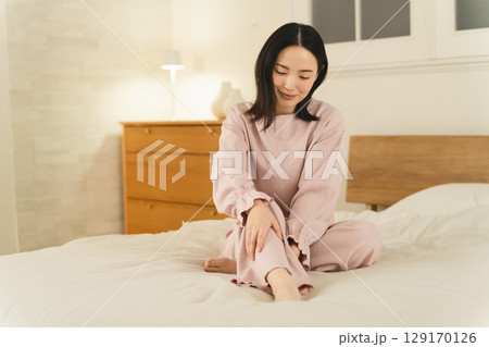 ベッドの上でストレッチをする若い女性 ビューティイメージ ベッドの上でストレッチをする若い女性 ビューティイメージ 129170126