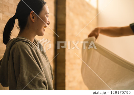 若い女性にタオルで熱波を当てる若い男性 ビューティイメージ 若い女性にタオルで熱波を当てる若い男性 ビューティイメージ 129170790