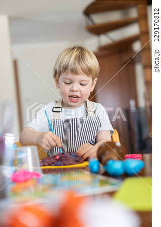 Blond boy sculpts from plasticine at home at the table. The idea and concept of the school, home education and developmental activities. 129170812