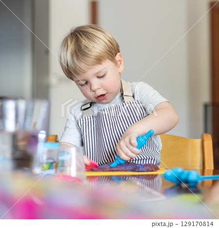 Blond boy sculpts from plasticine at home at the table. The idea and concept of the school, home education and developmental activities. 129170814