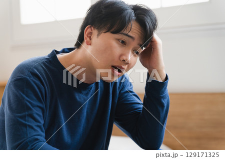 頭痛を覚える寝起きの若い男性　ライフスタイルイメージ 129171325