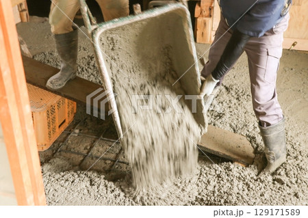 男性の作業員2人が一輪車からコンクリートを流し出している　　　 129171589