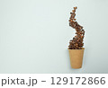 Flat lay with coffee beans poured from paper cup, on blue background, usable in food industry or product displays 129172866