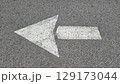 White painted arrow on asphalt road surface, representing direction and navigation in transportation contexts. 129173044