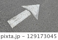 White painted arrow on asphalt road surface, representing direction and navigation in transportation contexts. 129173045