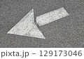 White painted arrow on asphalt road surface, representing direction and navigation in transportation contexts. 129173046