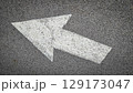 White painted arrow on asphalt road surface, representing direction and navigation in transportation contexts. 129173047