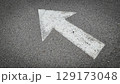 White painted arrow on asphalt road surface, representing direction and navigation in transportation contexts. 129173048