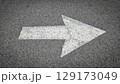 White painted arrow on asphalt road surface, representing direction and navigation in transportation contexts. 129173049