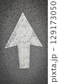 White painted arrow on asphalt road surface, representing direction and navigation in transportation contexts. 129173050
