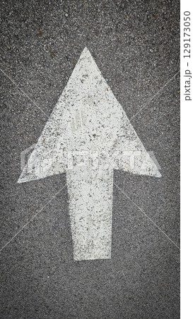 White painted arrow on asphalt road surface, representing direction and navigation in transportation contexts. 129173050