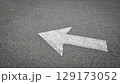 White painted arrow on asphalt road surface, representing direction and navigation in transportation contexts. 129173052