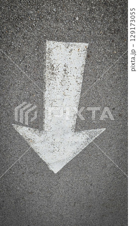 White painted arrow on asphalt road surface, representing direction and navigation in transportation contexts. 129173055