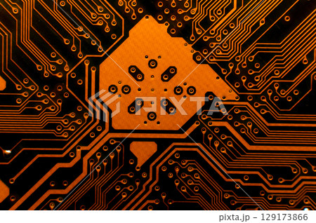 Orange computer circuit parts in neon light. Macro photo of a board painted in red tones Orange computer circuit parts in neon light. Macro photo of a board painted in red tones 129173866