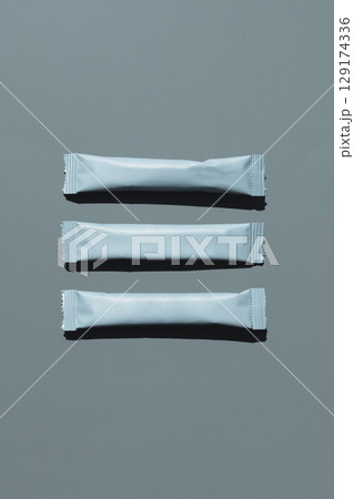 Three grey sachets with shadow on monochrome background. Three grey sachets with shadow on monochrome background. 129174336