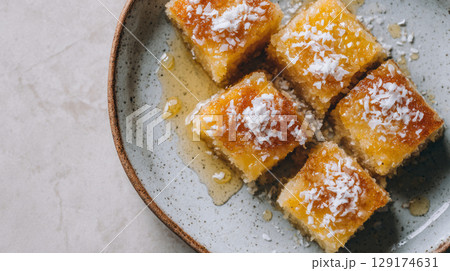 top view, plate of freshly baked basbousa squares with coconut flakes and syrup glistening 129174631
