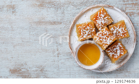top view, plate of freshly baked basbousa squares with coconut flakes and syrup glistening 129174636