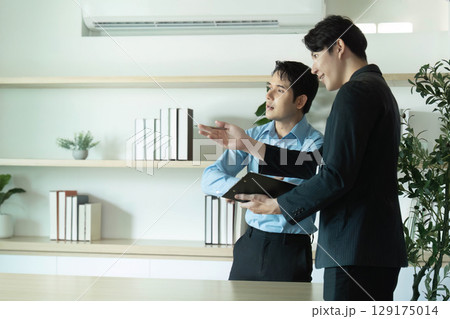 Client Consultation. Two businessmen discussing project details in a modern office. 129175014