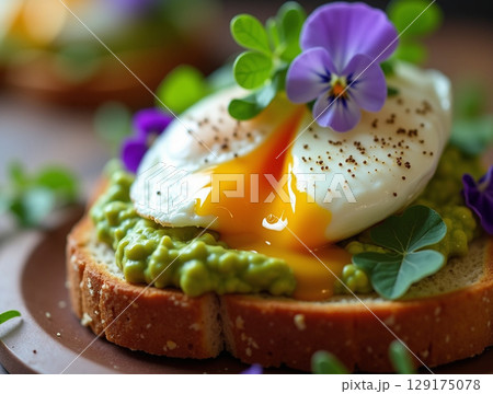 Close-up of Gourmet Avocado Toast with Poached Egg, Violas, and Microgreens 129175078