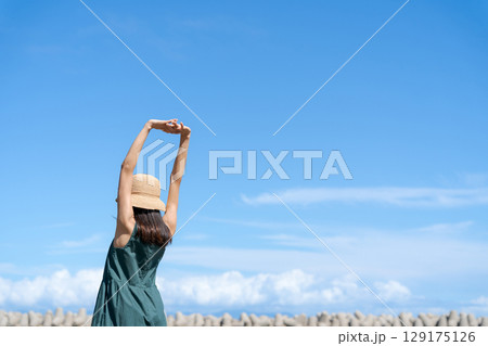 青い海に立つ若い女性 129175126