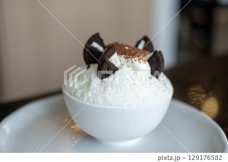 Shaved ice or Bingsu with chocolate powder and cookie on the top, served in a bowl 129176582