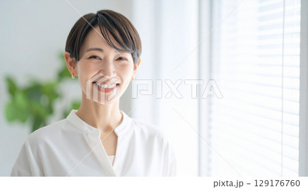 明るい室内で笑顔を見せるショートヘアの40代日本人女性のポートレート　ビジネスウーマン 129176760