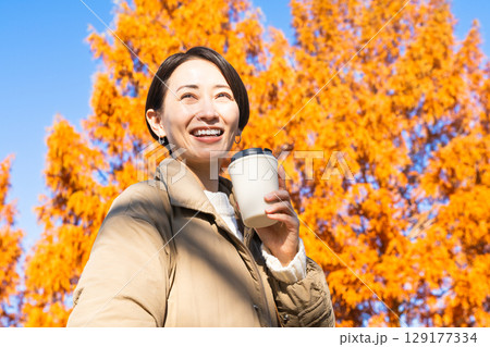 紅葉を楽しみながらホットドリンクを飲む女性 ライフスタイルイメージ 紅葉を楽しみながらホットドリンクを飲む女性 ライフスタイルイメージ 129177334