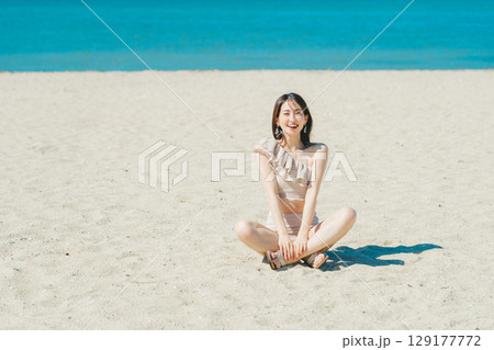 砂浜に座る水着の若い女性 砂浜に座る水着の若い女性 129177772