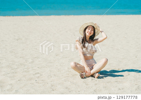 砂浜に座る水着の若い女性 129177778