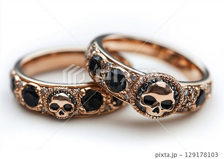 Pair of gold wedding rings with a skull pattern on a white background. Original style. 129178103