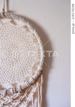 White dreamcatcher hanging on a white wall. Boho interior decor 129178296