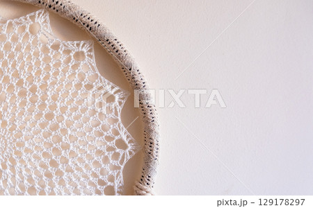 White dreamcatcher hanging on a white wall. Boho interior decor 129178297