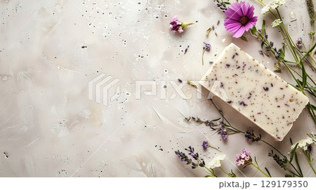 Lavender-infused soap with flowers on beige surface. Soothing setup for spa or wellness themes. Great for organic or skincare designs. 129179350