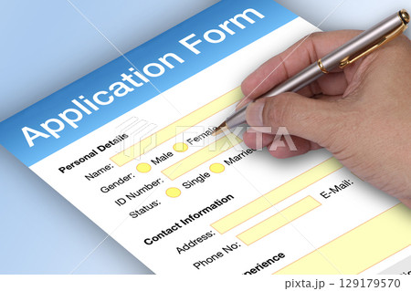Hand holding pen to writting application form. 129179570