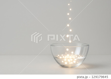Drops of light fall into a glass bowl. Space for text. 129179645