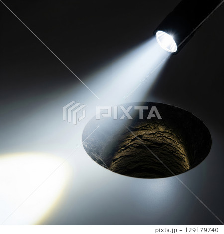 The beam of the flashlight illuminates a deep hole. 129179740