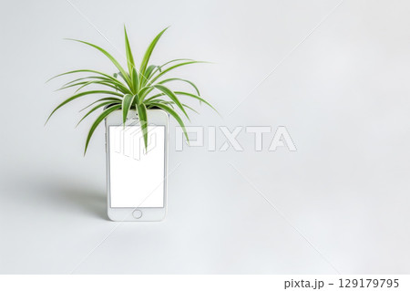 A smartphone with a plant growing out of a screen. Space for text. 129179795