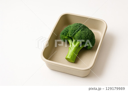 One broccoli in a container on a light background. Space for text. One broccoli in a container on a light background. Space for text. 129179989