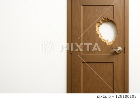 A wooden door with a round hole, a light wall. Space for text. A wooden door with a round hole, a light wall. Space for text. 129180105