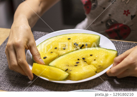 Close up shot of the cut watermelon with yellow flesh on ceramic plate 129180210