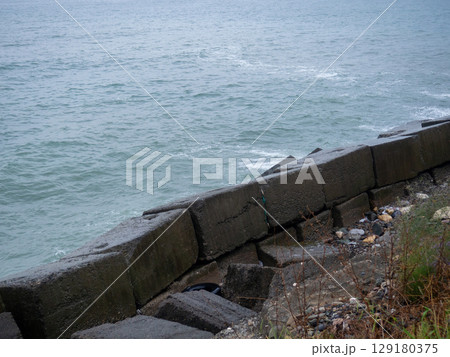 Old blocks of fortifications of the coast. Concrete structures on the shore. Protection against storms, waves and avalanches. 129180375
